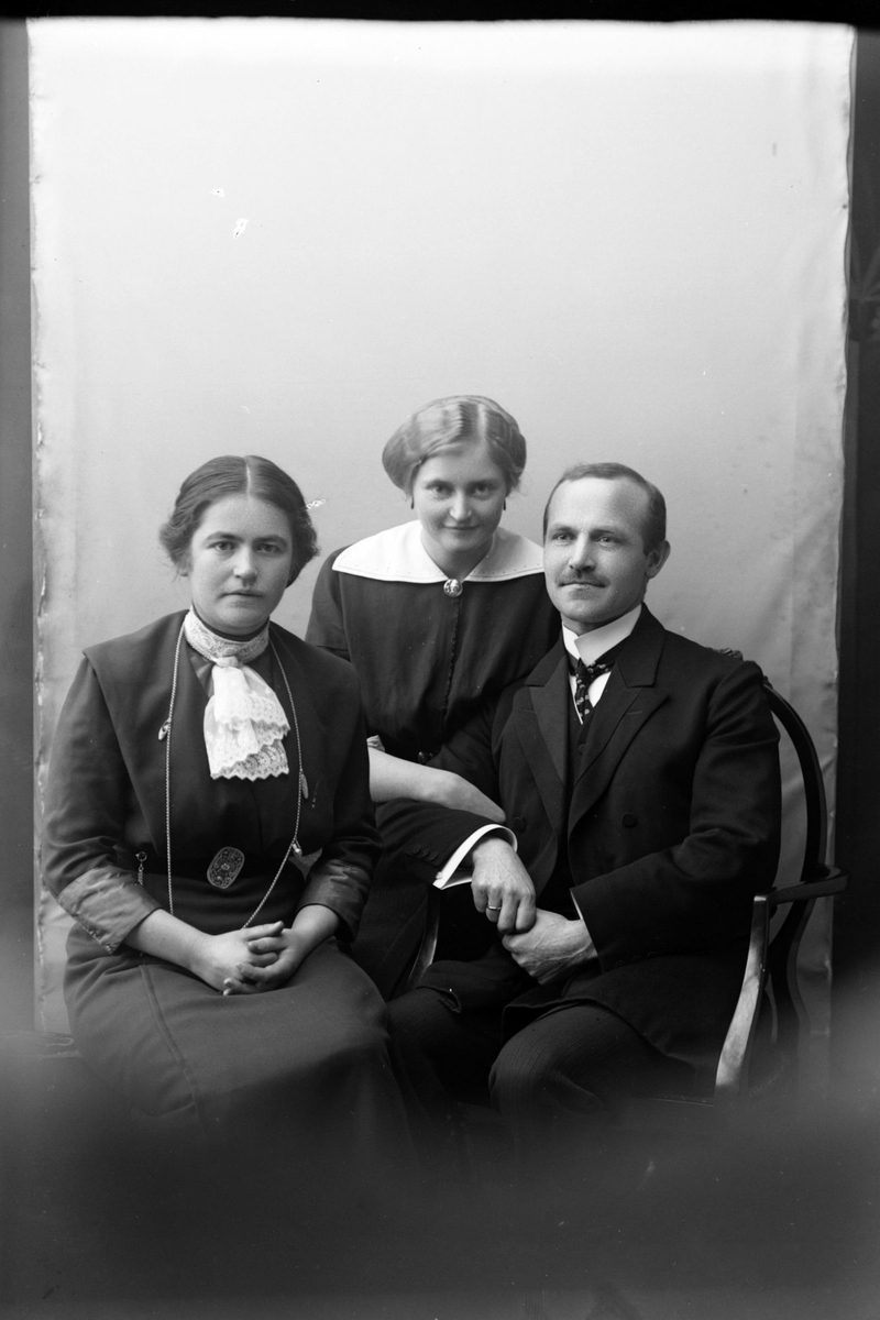 Studioportrett av tre sittende personer.