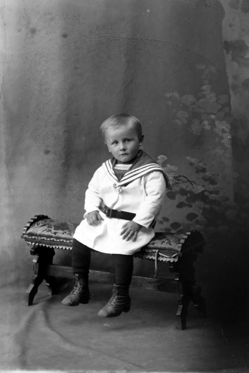 Studioportrett av en gutt som sitter.