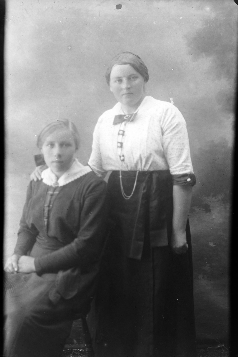 Studioportrett av en kvinne stående ved siden av en jente.