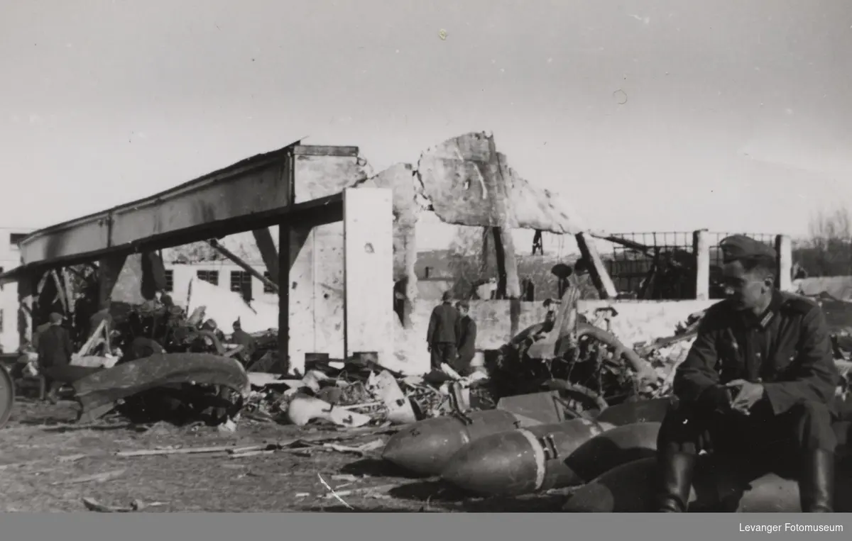 Betonghangar på Værnes ødelagt av britiske bombefly. To Junkers stjernemotorer ligger ved siden av bombene soldatene sitter på.
