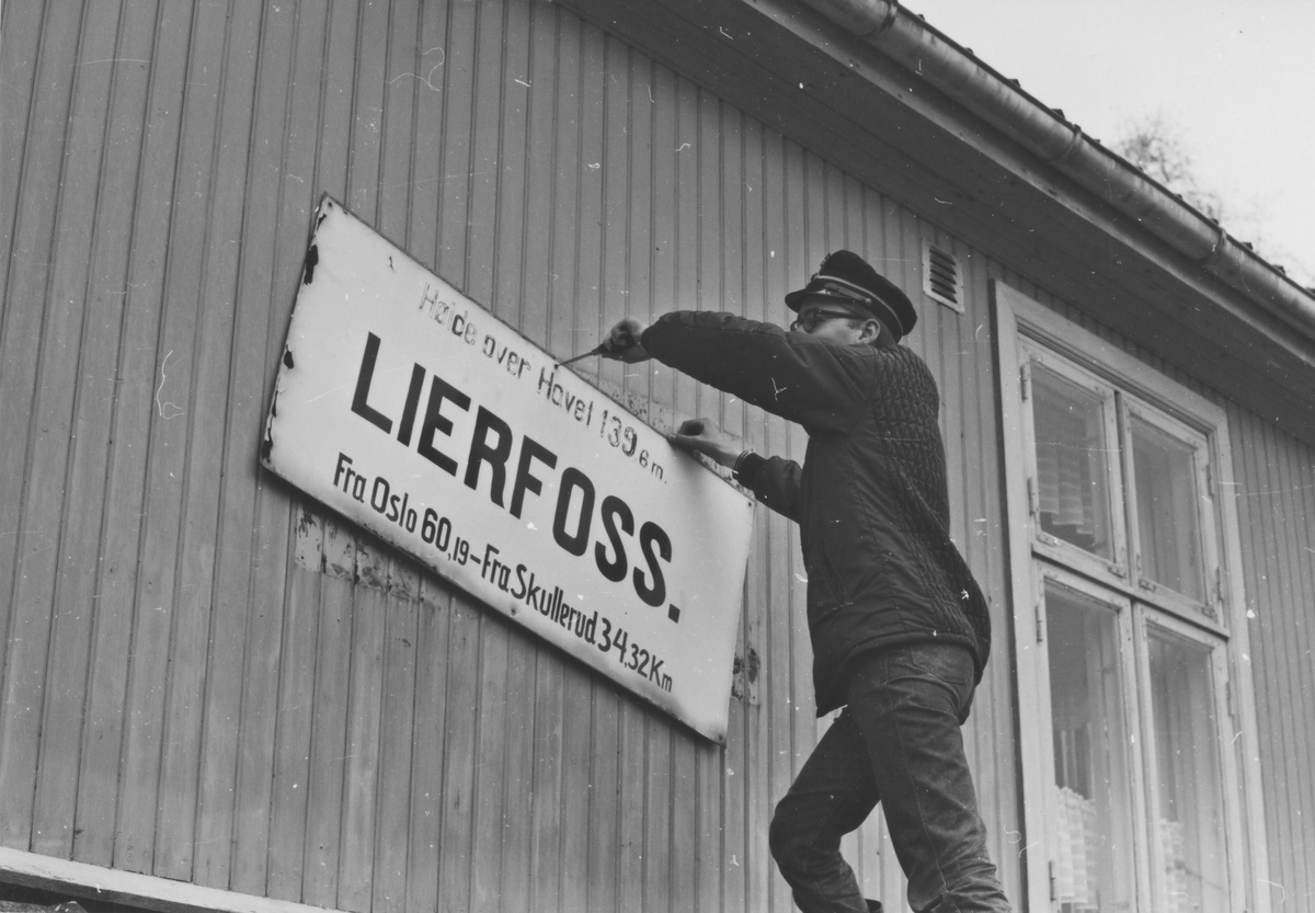 Fra Lierfoss stasjon noen år etter nedleggelsen. Stasjonsskiltet demonteres for overføring til museumsbanen.
