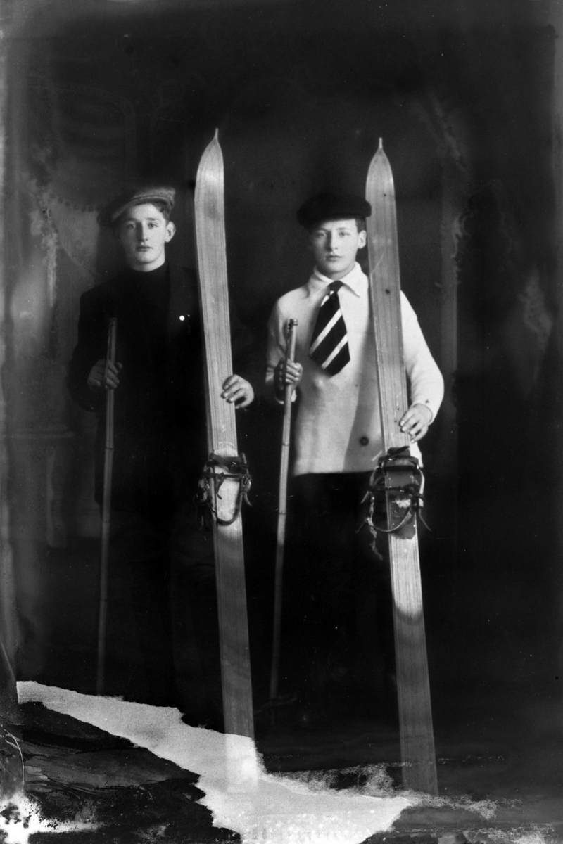 Studioportrett av to gutter med ski.