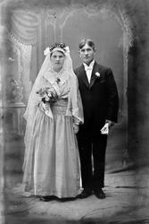 Studioportrett av et brudepar i helfigur.