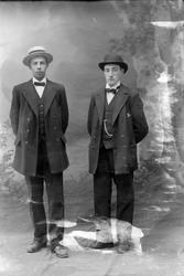 Studioportrett av to menn med hatter på hodet.