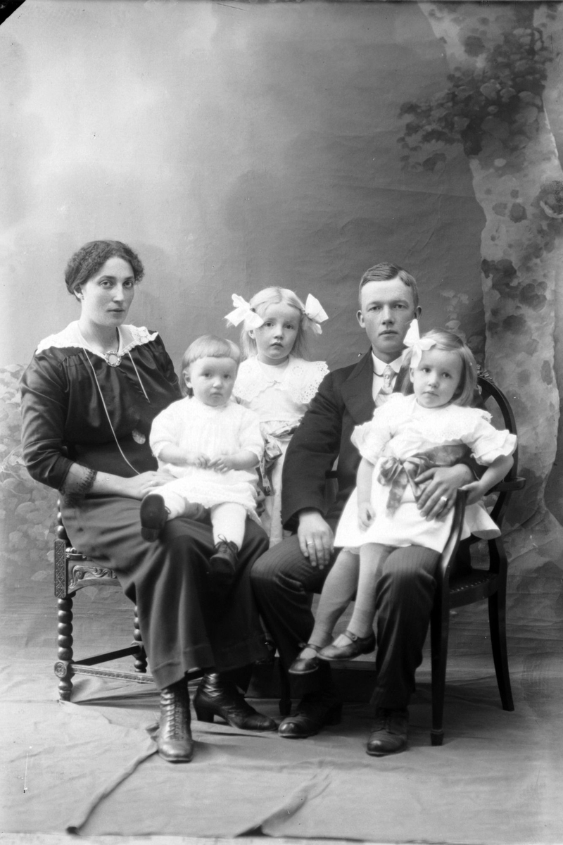 Studioportrett av en mann og kvinne med tre barn.