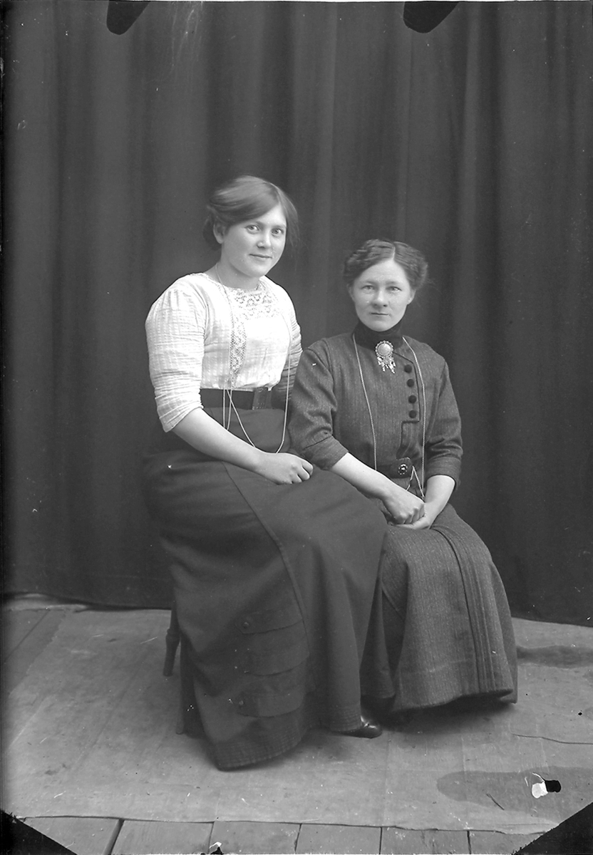 Portrett. To damer, begge sitter. Begge er også med på NM 8243:92, og damen til venstre er også med på NM 8243:91.