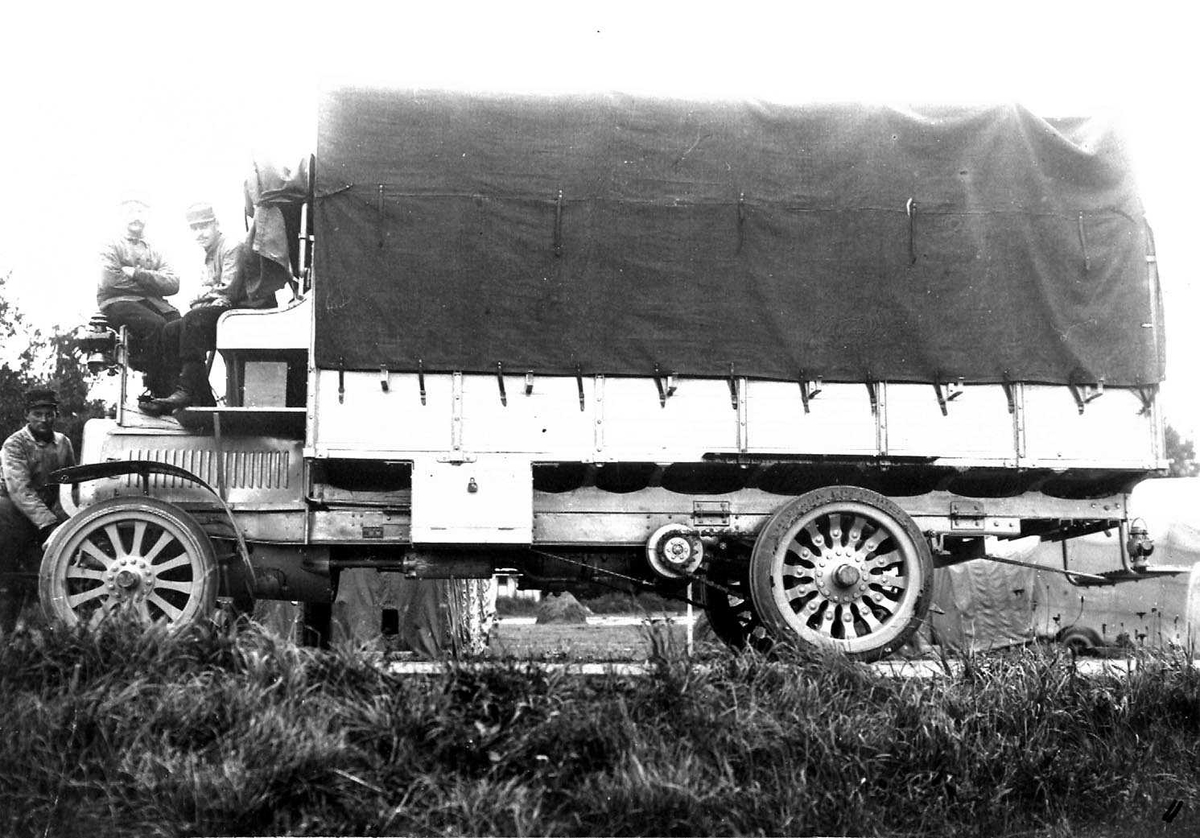 En parkert lastebil "Delahaye" brukt til å transportere militært personell. Tre personer, menn i militæruniform, på kjøretøyet.