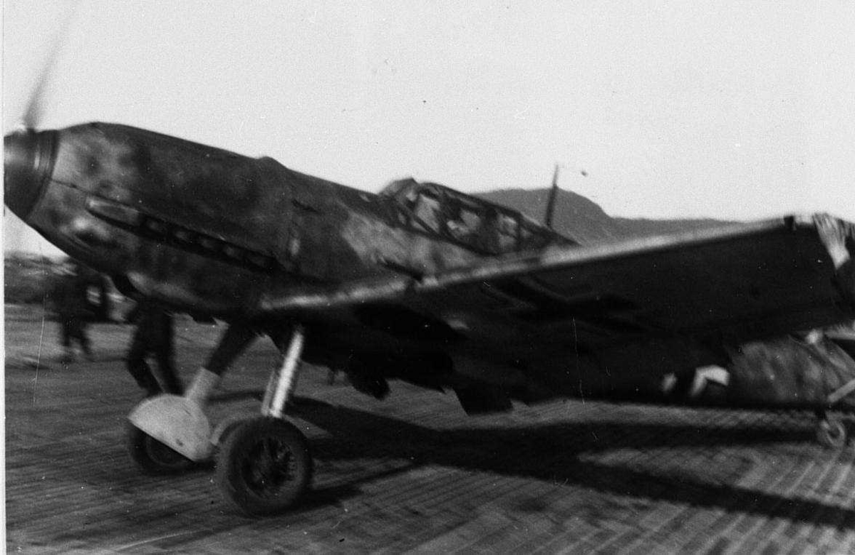 Lufthavn. tysk militert fly på bakken Bf109. Personer ved flyet.