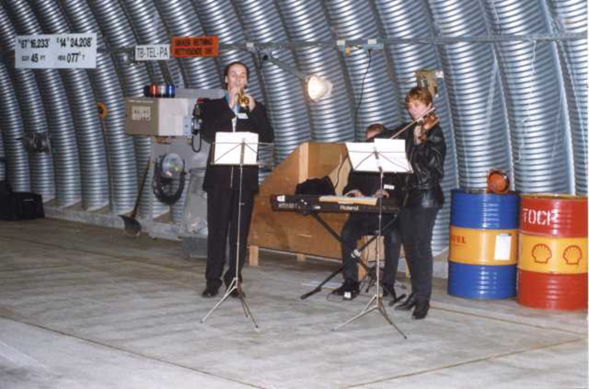 Lufthavn (flyplass). Tremansorkester spiller inne i en hangar.