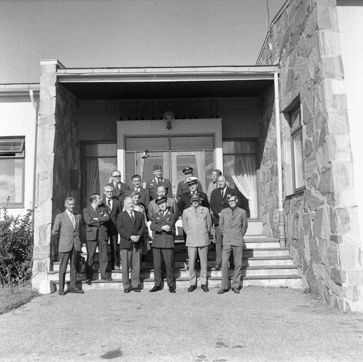 Gruppefoto av Forsvarskommiteens besøk på Bodø flystasjon, her fotografert foran Messe II på stasjonen. Oberstløytnant Olav F. Aamoth sees i første rekke som nr. 3 fra høyre. Oberst H. Wergeland sees helt bakerst i midten.