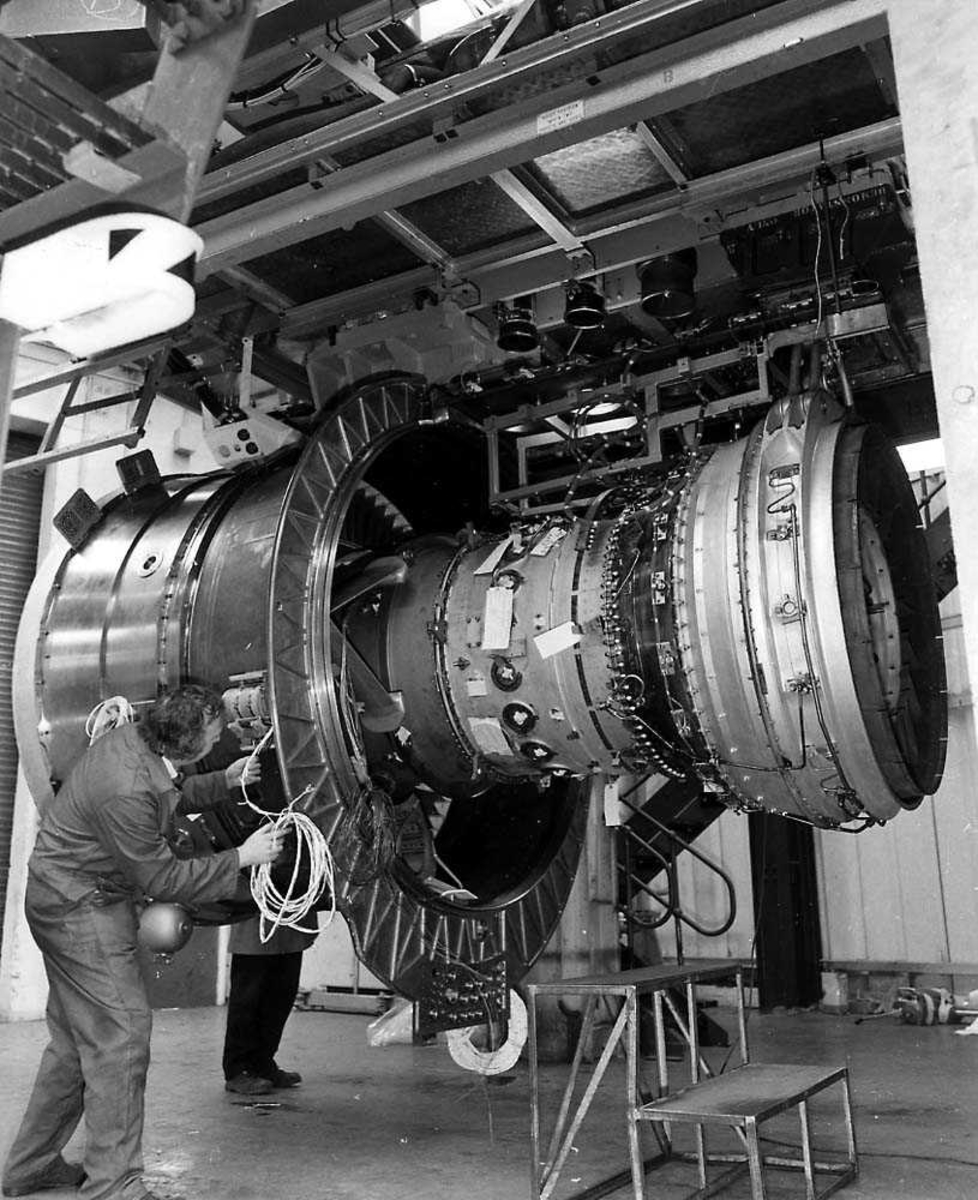 En flymotor inne i en bygning, Rolls-Royce RB 211-535C. En person som arbeider på motoren.