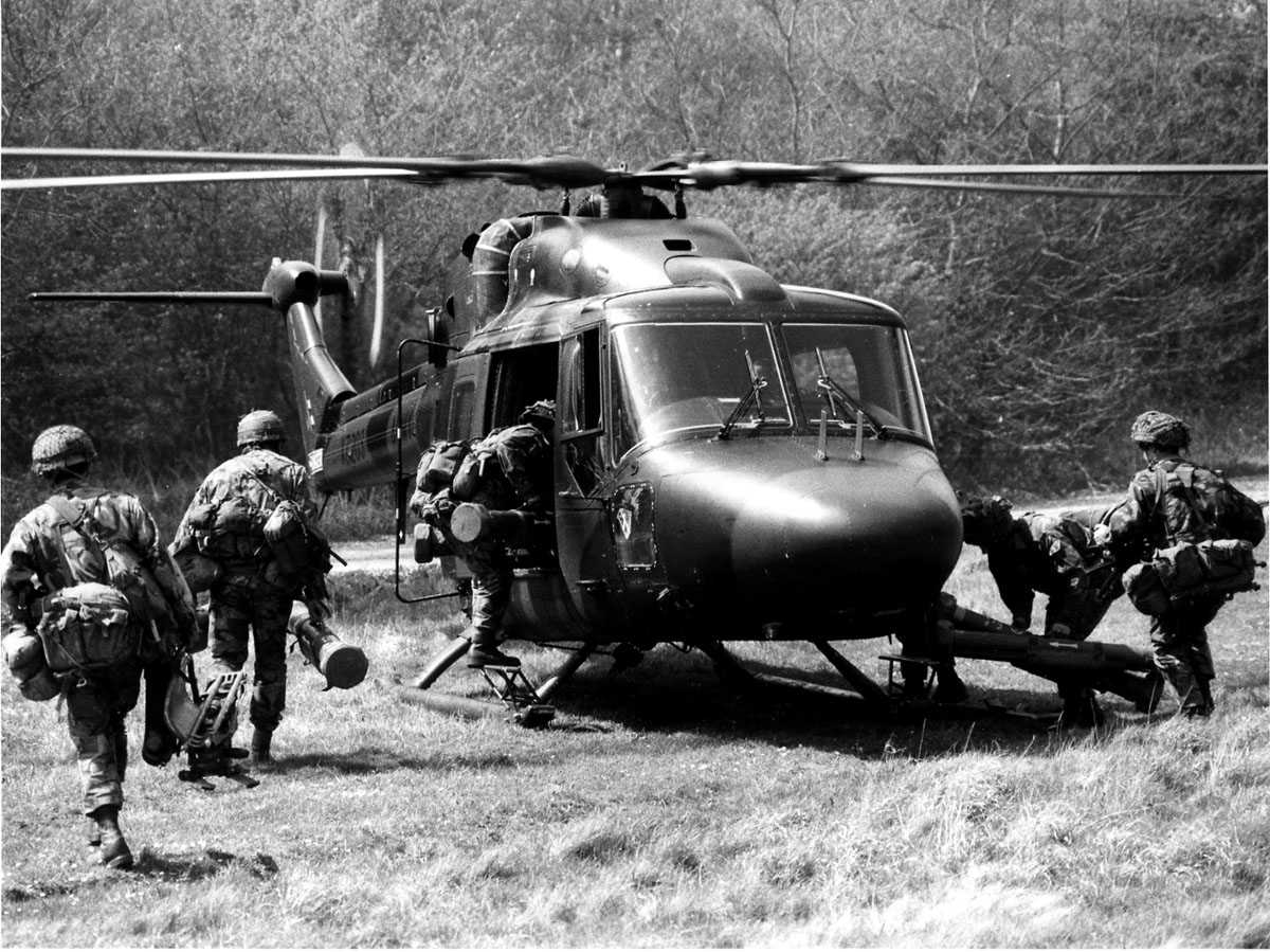 Ett helikopter på bakken. Westland Lynx AH Mk.9 tilhørende Royal Army merket XZ203. 6 soldater med full utrustning på vei inn i helikopteret. (Anti-tank)