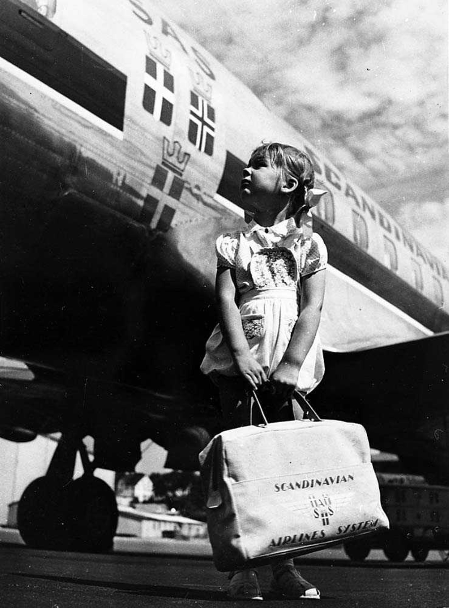 Lufthavn. Ett barn som som står med en bag i hånden foran ett fly fra SAS.