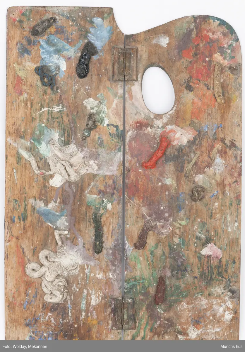 Malepalett i tre. Paletten er brukt og har mange spor av maling i ulike farger.