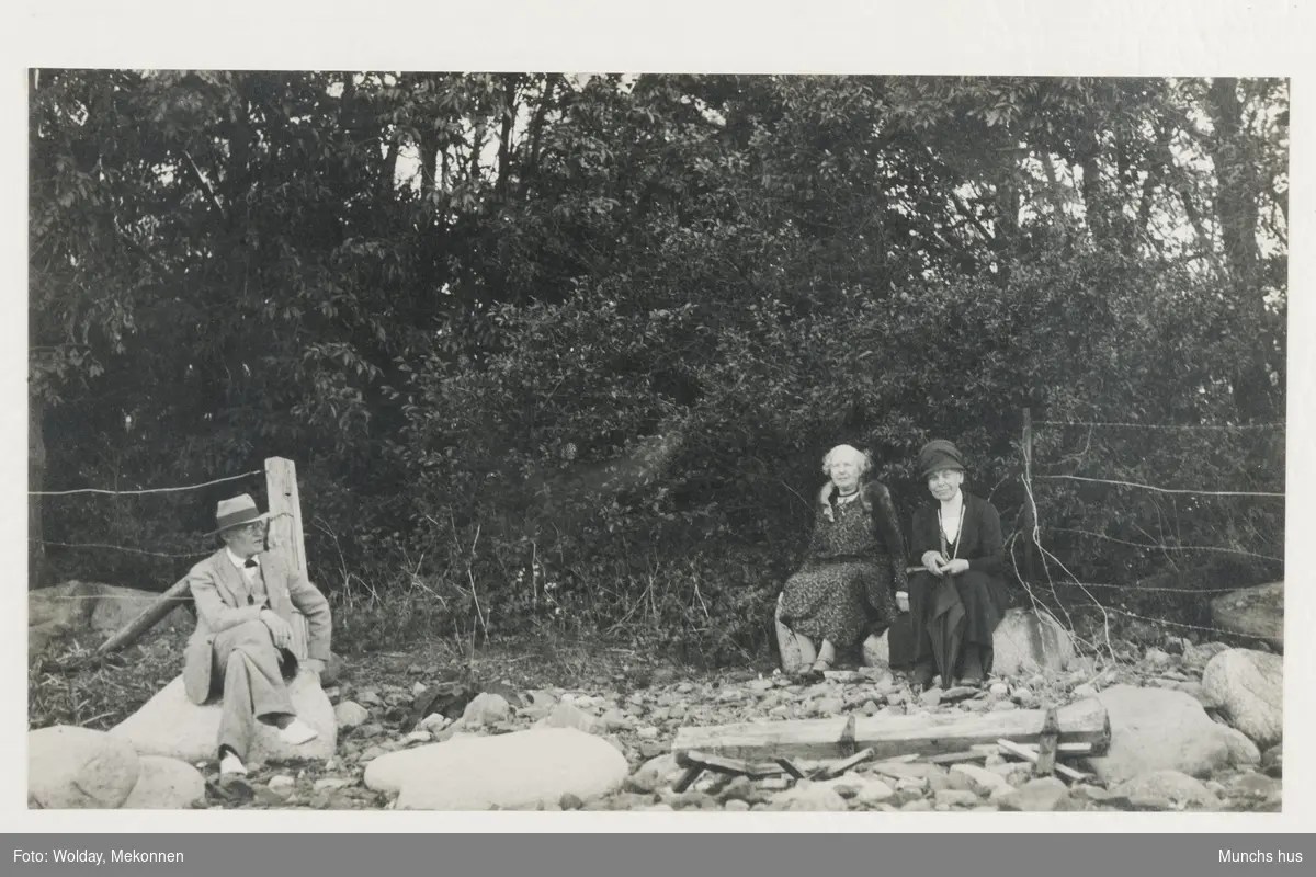 "Edvard Munch sittende ved stranden, nedenfor sitt lille hus i Aasgaardstrand, sammen med sine gjester, kusinene Alfild og Eva Munch".