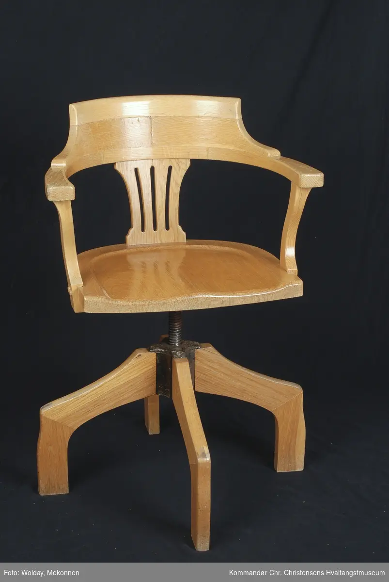 Trestol. Svingstol med armlener. Lakkert. Regulerbar høyde. Gjengemekanisme, kobling av jern, fire ben. Messingskilt på stolrygg viser navn på alle direktørene ved FMV og deres virkeperiode. 
Jerndelene i "stativet" er rustet. Lakken flasser av. Øvre del av ryggen har falt av. Trestykket kan trolig limes på. Det fulgte en tykk grønn setepute med stolen.