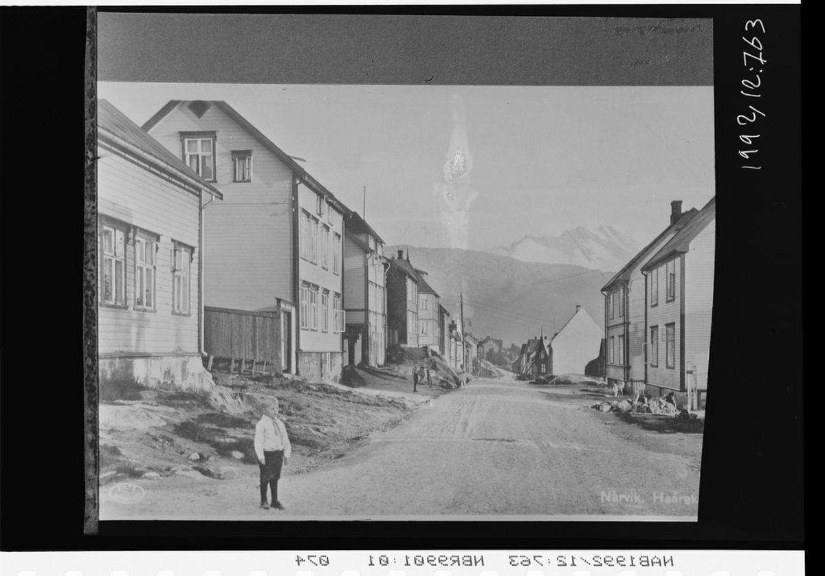 Håreks gate (Haareks gate), Narvik. Gutt stående i veikanten. Sovende dronning i bakgrunnen.