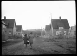 To jenter går nedover ei rett gate i Kirkenes.  Jentene bære