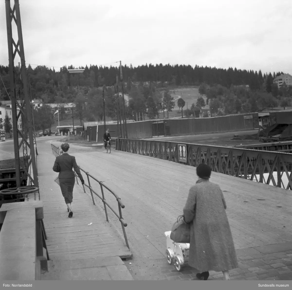 Två kvinnor, en med  barnvagn, promenerar norrut över den gamla svängbara Tivolibron.