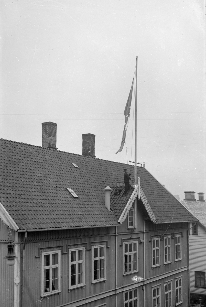 Det gamle rådhuset i Haugesund. En mann står på taket og heiser flagg ...