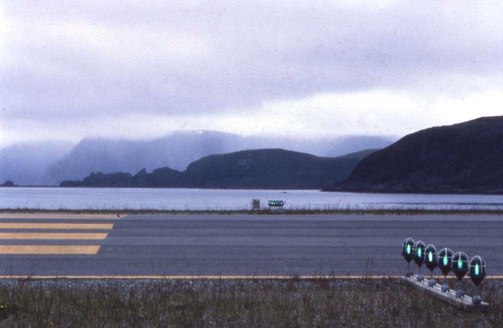 Lufthavn. Honningsvåg. Foran på bildet krysser rullebanen og i bakgrunnen Kamøyfjorden og Selvågklubben.