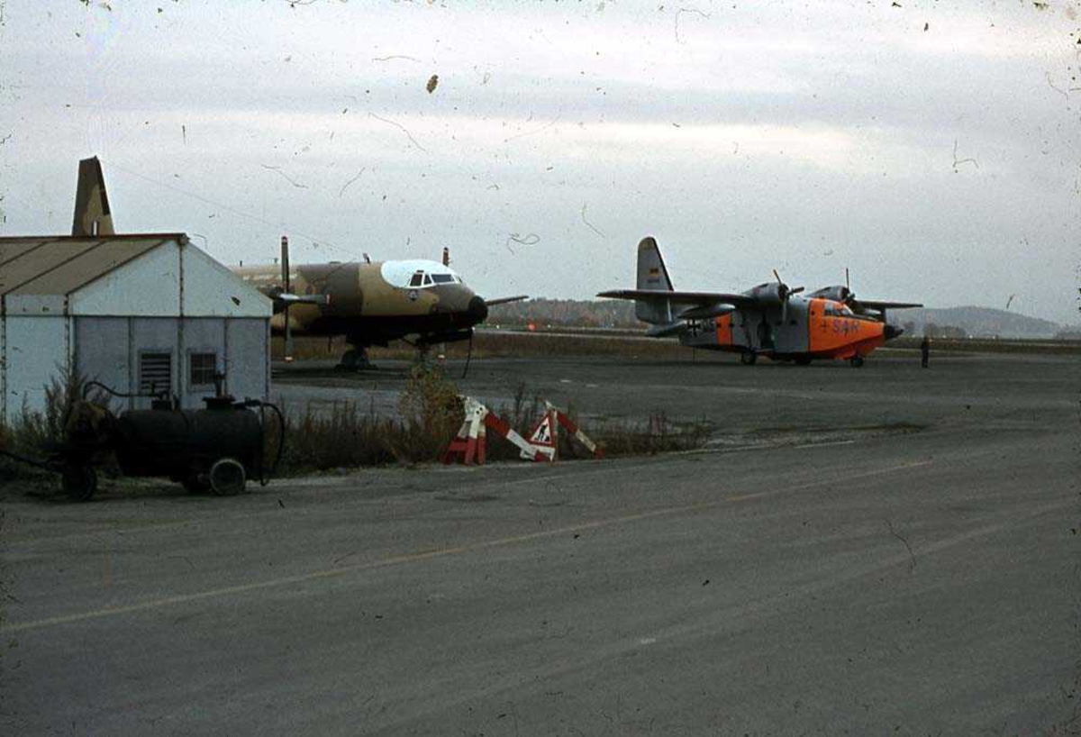 Lufthavn. Ett fly på bakken, Grumman HU-16 Albatross. Et annet fly ved siden av.