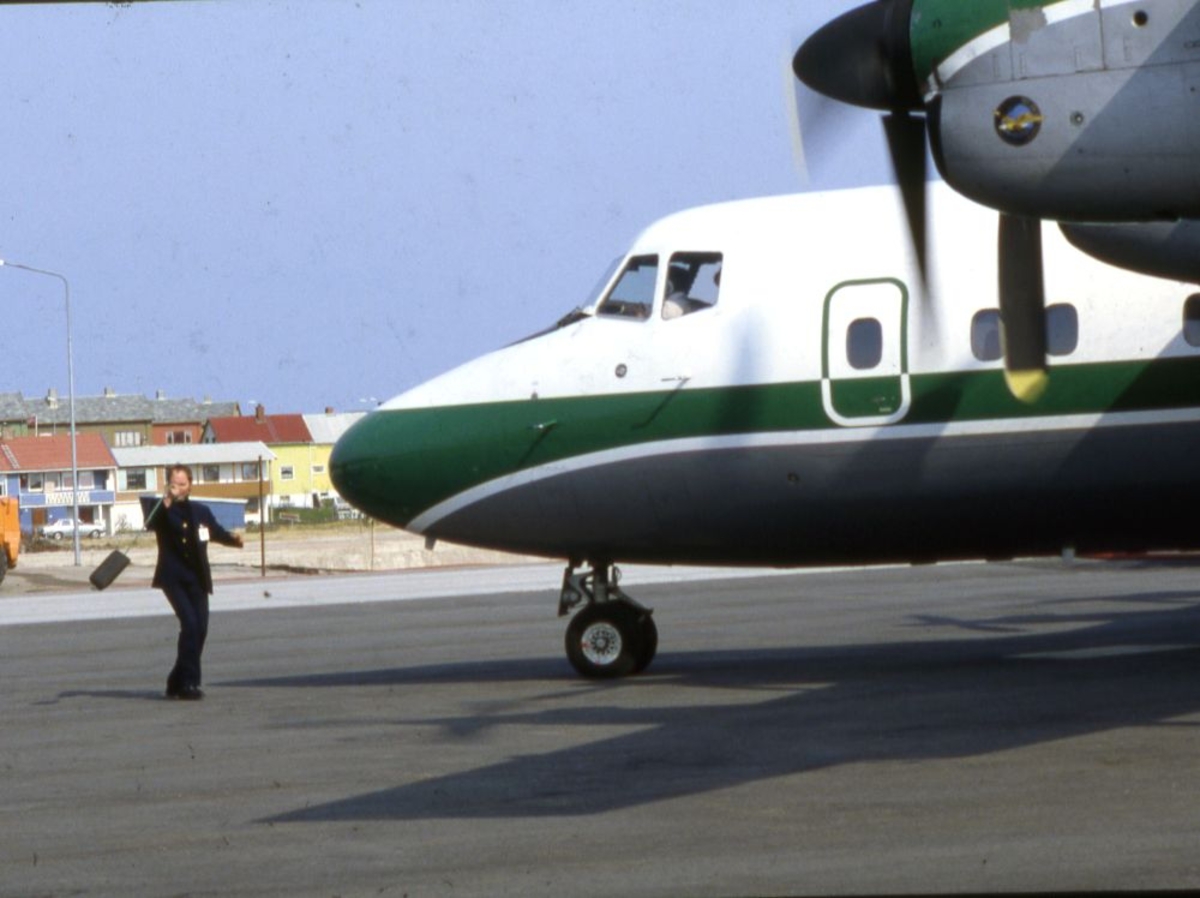 Lufthavn (flyplass). Et fly, DHC-7-102 Dash 7 fra Widerøe parkert. En person foran flyet.
