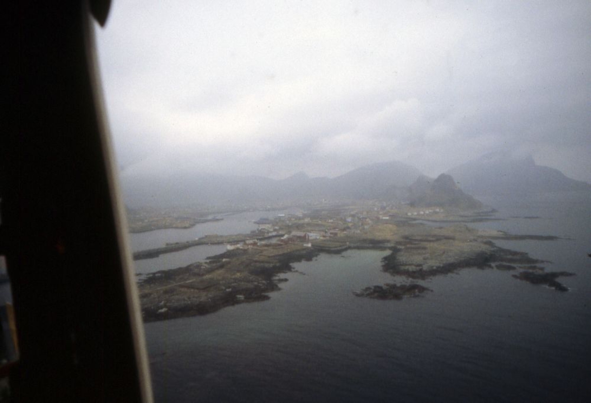 Luftfoto. Et fly,  DHC-6-300 Twin Otter fra Widerøe passerer Værøy.