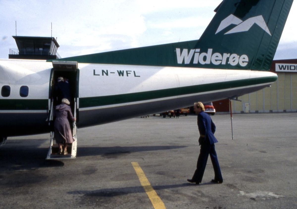 Lufthavn (flyplass). Et fly, LN-WFL, DHC-7-102 Dash 7 fra Widerøe parkert. To passasjerer går ombord og bak følger en flyger (pilot).