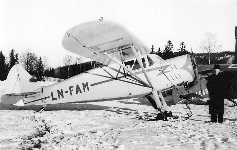 Åpen plass, Ett fly med skiunderstell på bakken, LN-FAM, Hønningstad Norge A. Litt av annet fly i bakgrunnen, LN-EAB. En person ved flyet. Snø på bakken.
