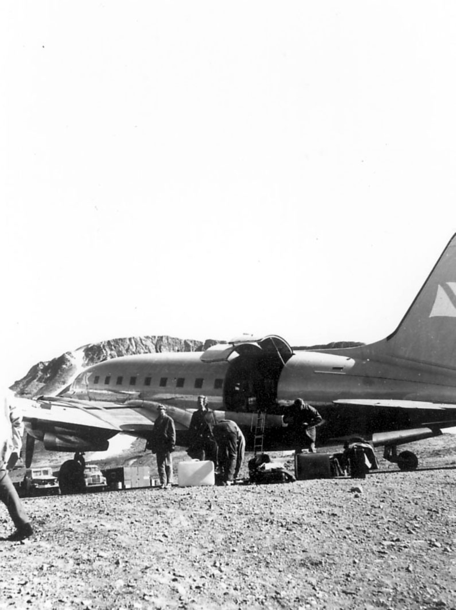 Åpen plass, ant. lufthavn. Ett fly på bakken, Curtiss C-46A-45-CU Commando, LN-FOR. Flere personer og reisegods ved flyet.
