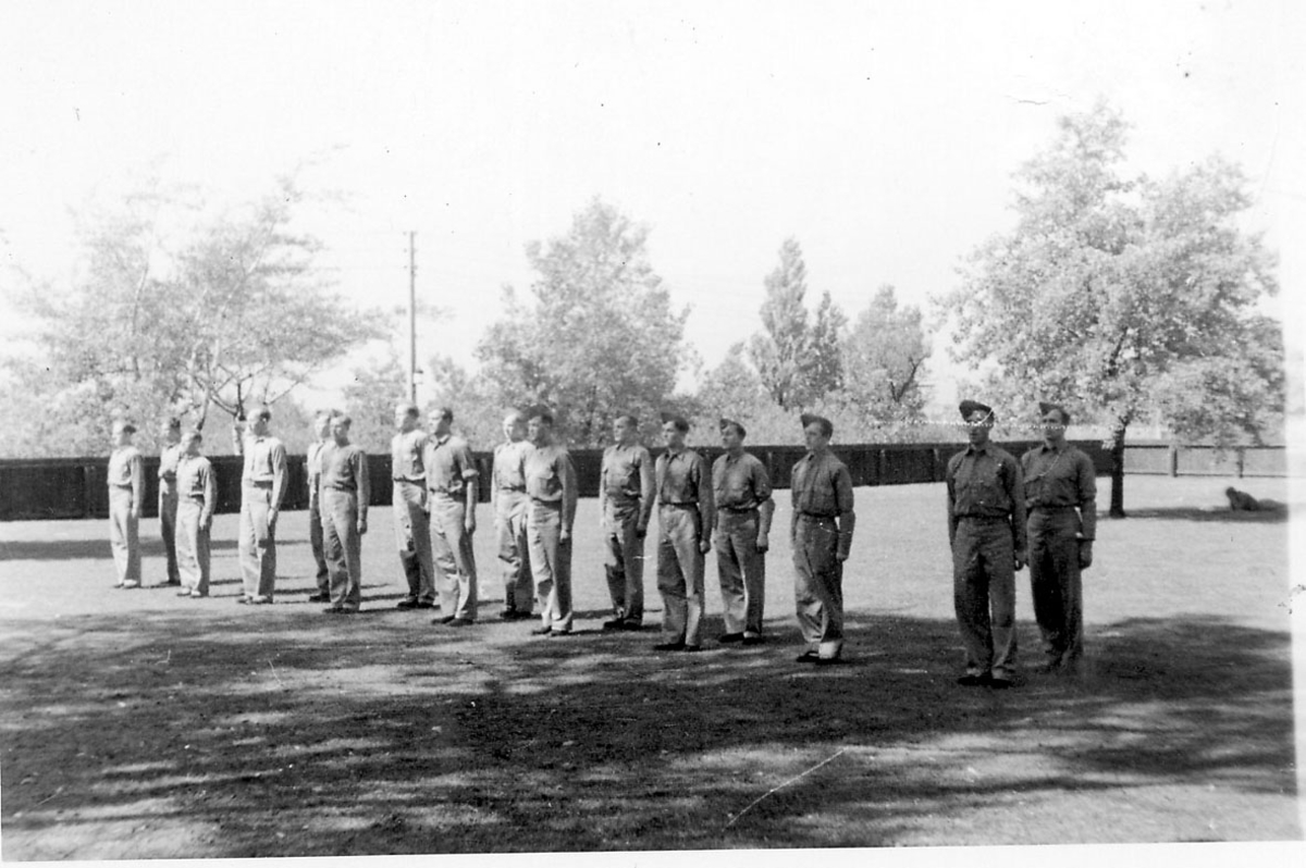Gruppeportrett, en gruppe soldater i militæruniform, ant. rekrutter, oppstilt på åpen plass.