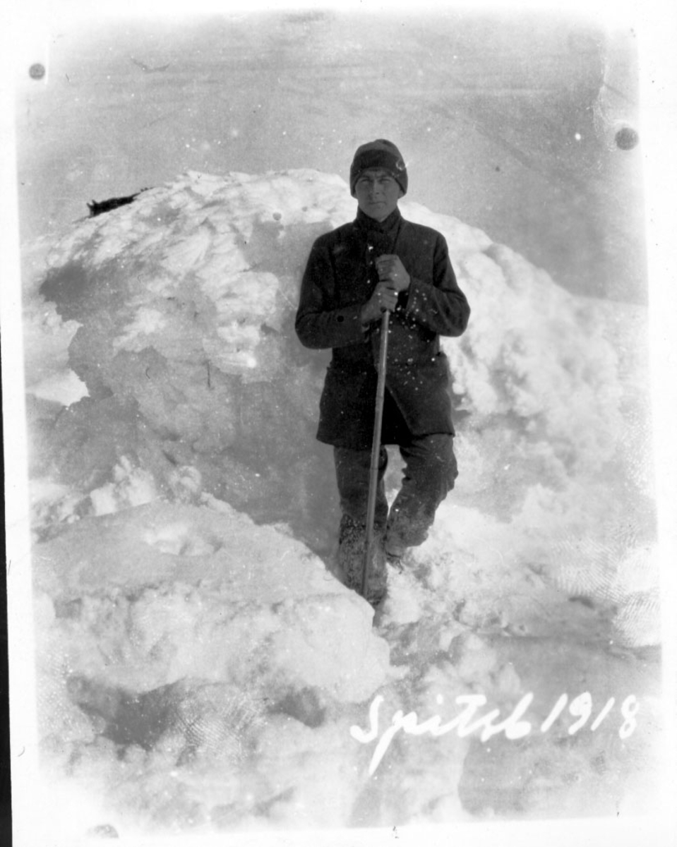 1 person foran snøhaug, med spade e.l. i hendene.