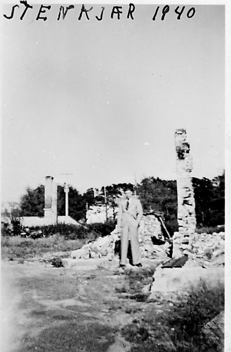 Ruiner, 1 person sitter i ruinene i forgrunnen. Steinkjær under 2. verdenskrig.