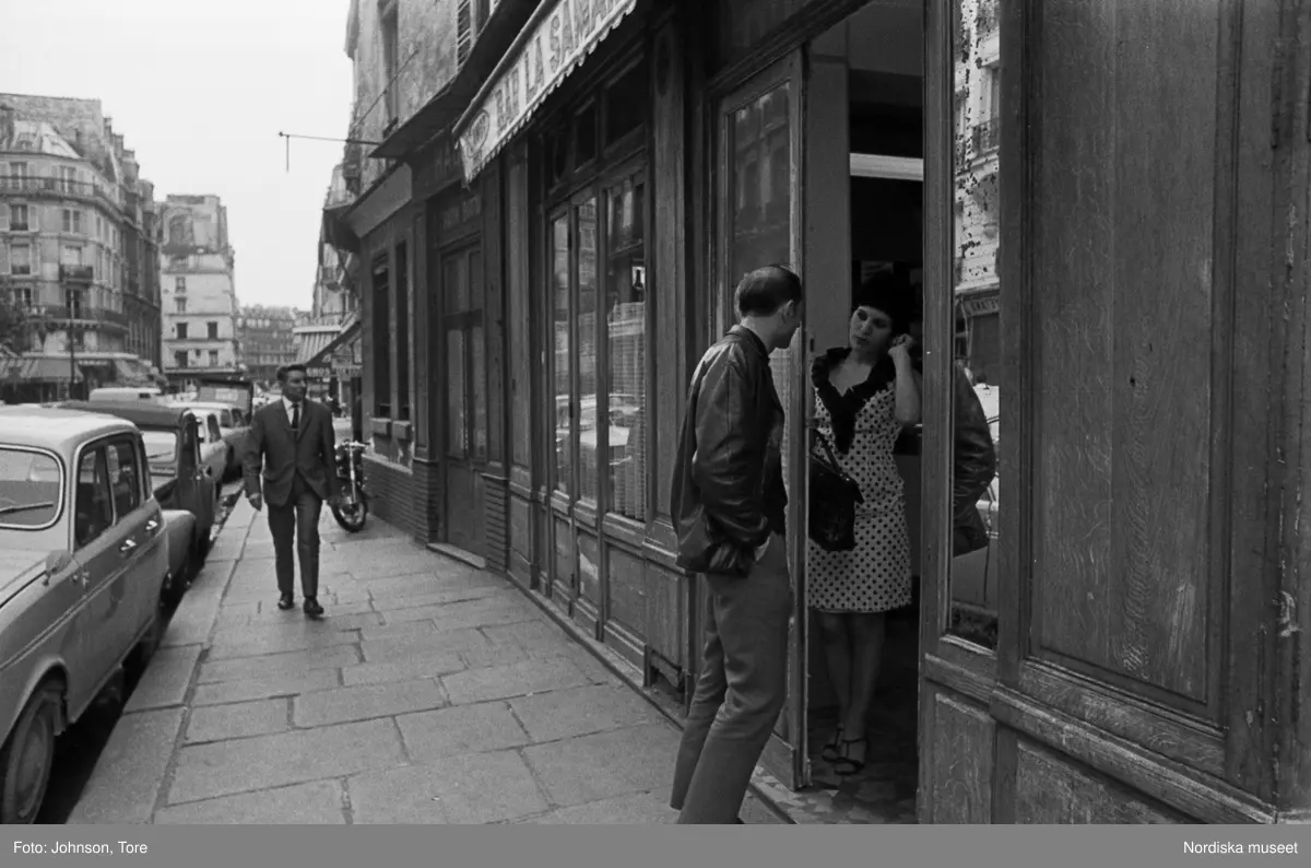 En man pratar med en kvinna vid dörren till en bar, Paris