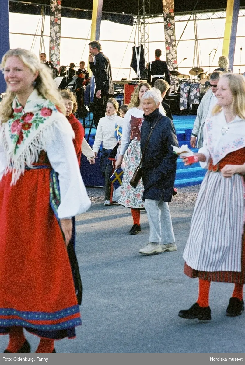Firandet av den svenska nationaldagen den 6 juni 2004 på Skansen. Människor iklädda folkdräkt. Näsby Parks Scoutkår. Blomsterarrangemang.