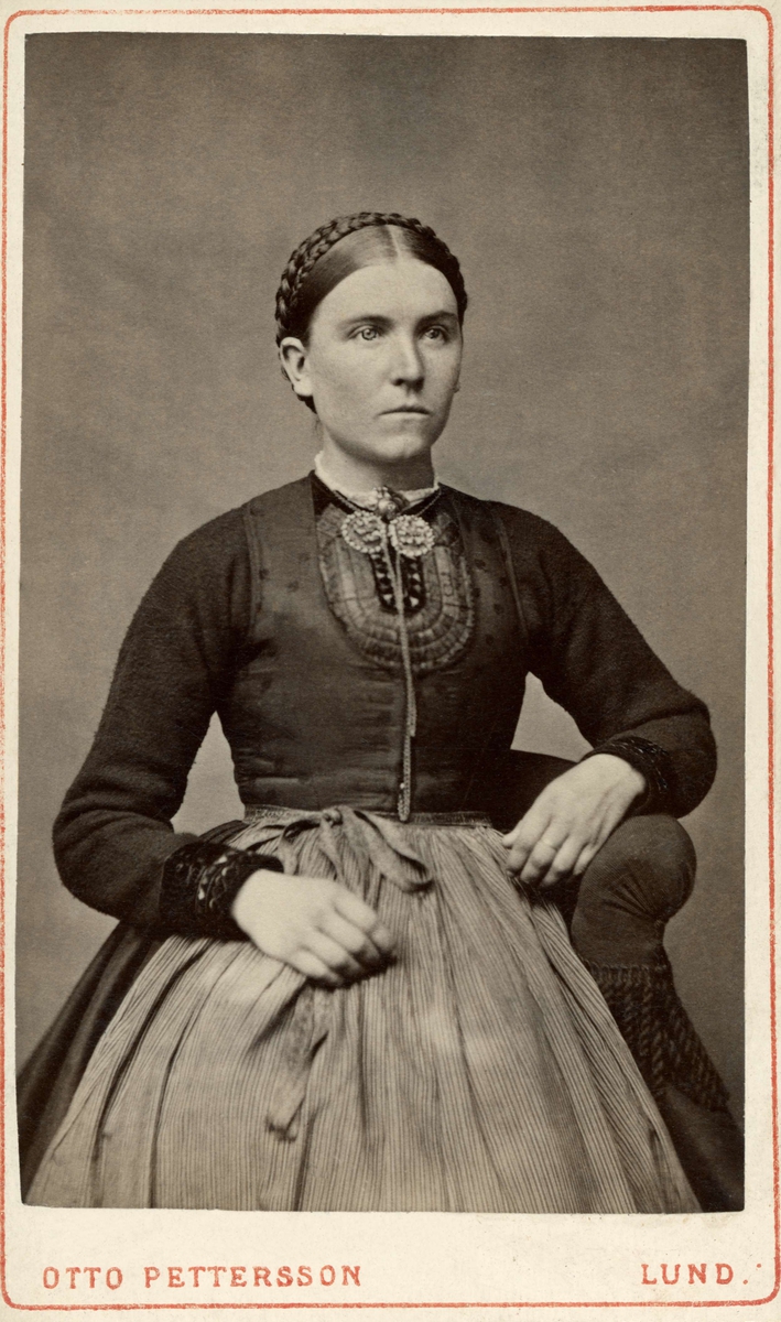 Kvinna från södra Skåne klädd i stickad tröja s.k. spedetröja med dekor kring halsringning och ärmkanter samt med livstycke.