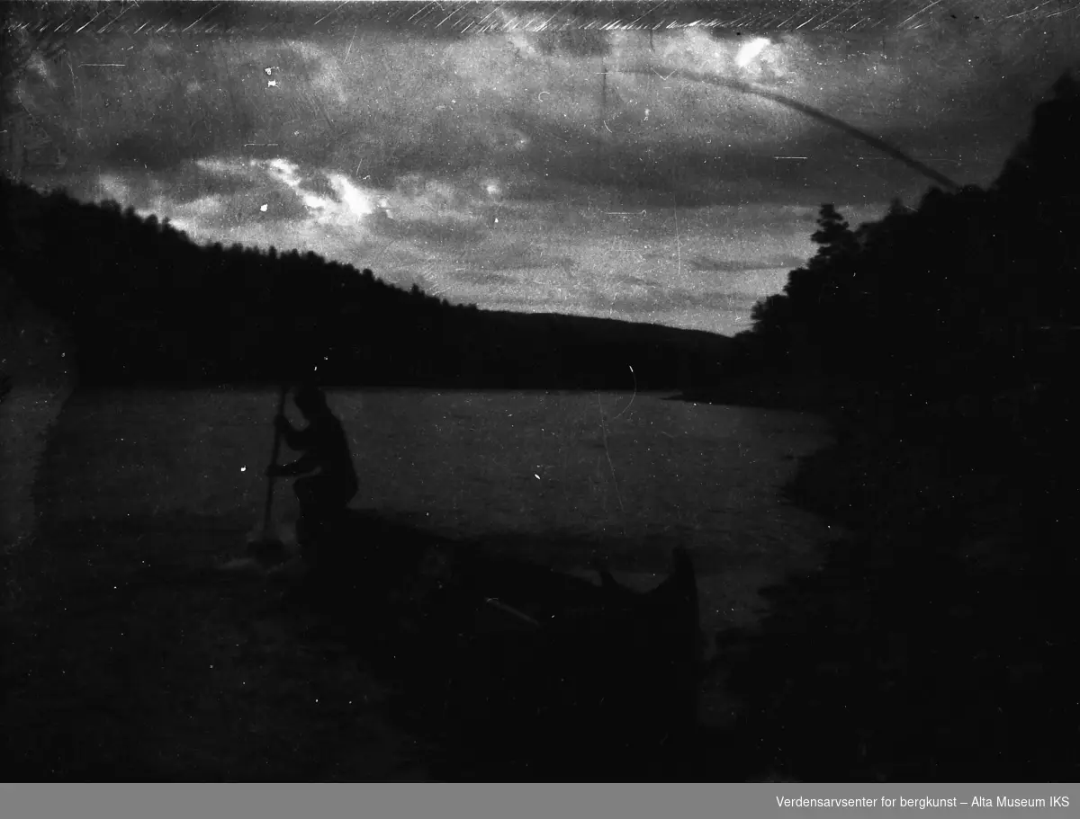 En mann tar en laks med klepp fra elvebåten.
Bildet er tatt i fiskesesongen på sommeren i 1949.