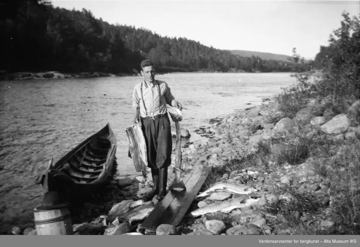 Brynjulf Myreng står med en partert laks i hånda på elvebredden.
Bildet er tatt i fiskesesongen på sommeren i 1949.