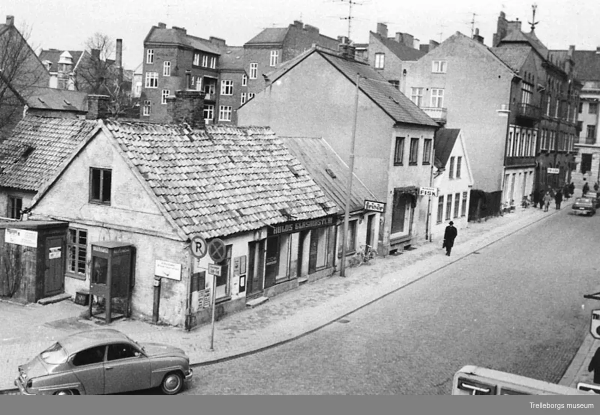 Kontinentgatan. Affärsfastigheter på Kontinentgatan i Trelleborg den 4/4 1960. Till vänster i bild Hulds Glasmästeri. Södra delen av huset upptogs av Perssons tobakshandel. I förgrunden en SAAB 95.