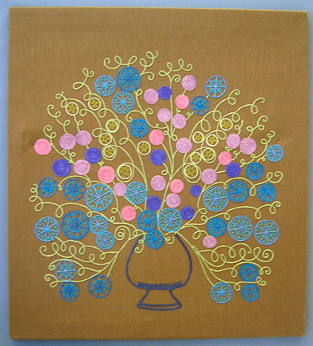 Bonad/broderad tavla. Modellnamn "Sofi". Mönstret komponerat av Anna Hådell 1977.
WLHF 995:1 - Tavla i brunt linnetyg med broderi i kulört lingarn utfört i kedjesöm. Mönster i form av en blomsterurna i blått med stiliserade blommor i blå, ljusgröna och rosa nyanser. Broderiet är fäst på en spännram med lim och häftklammer.
WLHF 995:2 - Provlapp. Brunt bottentyg i lin med påbörjat broderi i gråblått, blått, turkos, grönt och rosalila. Mått 115x270 mm.