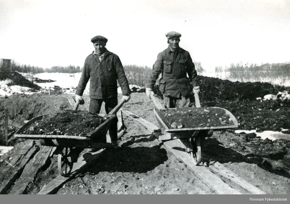 Bildet viser to veianleggsarbeidere med hver sin trillebåre, på strekningen Karlebotn - Gandvik.