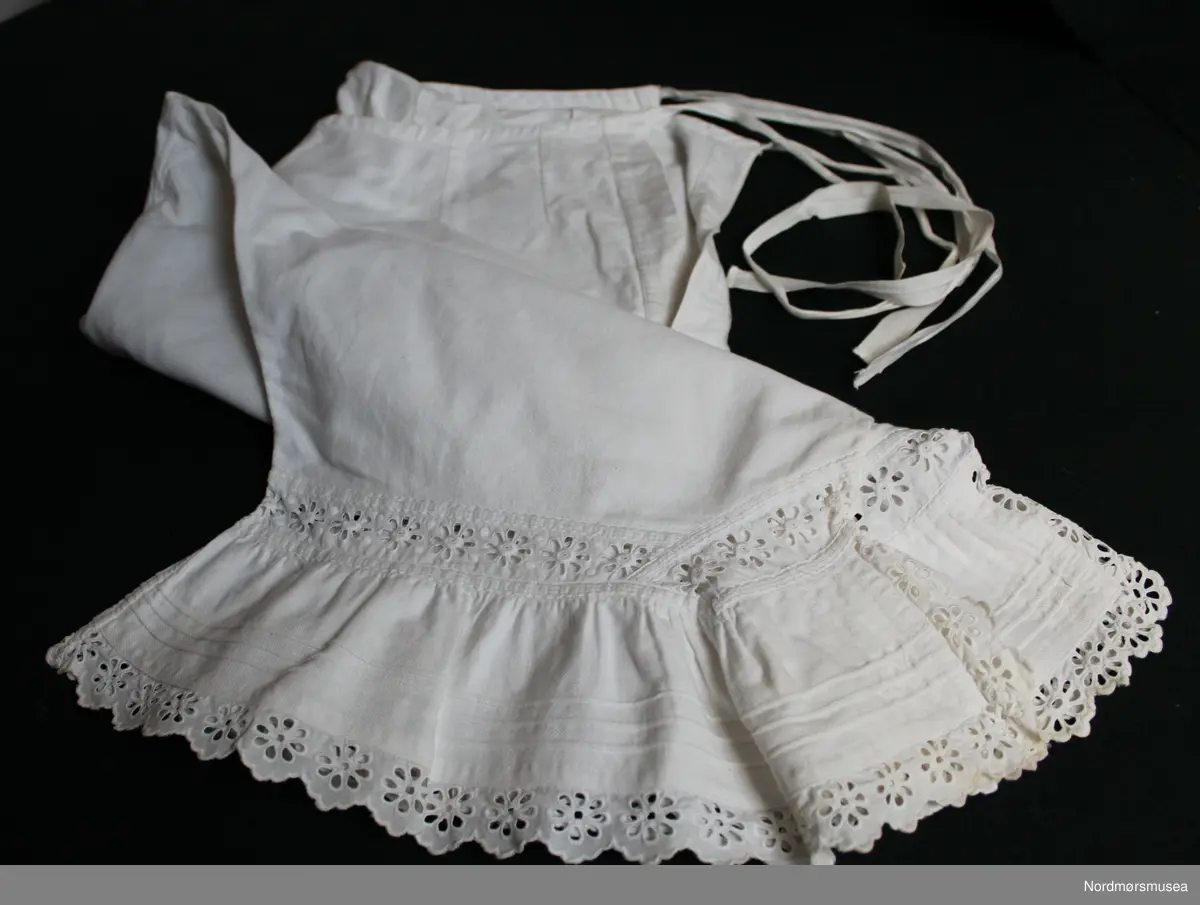 Knelang underbukse for dame. Maskinsøm i bomull. Knyting i begge sider i livet. Blonder i avslutning ved kneet.