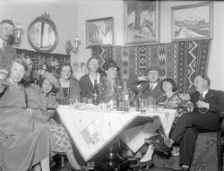 Kvinner og menn i en stue. Selskap hos Thorsrud med oppbundn