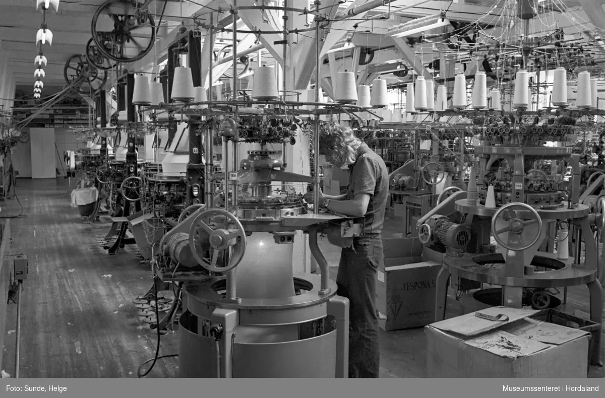 Arbeidsliv ved Salhus Tricotagefabrik i Salhus, Bergen i 1976. Arbeidar ved strikkemaskin på strikkeloftet ved Salhus Tricotagefabrik.