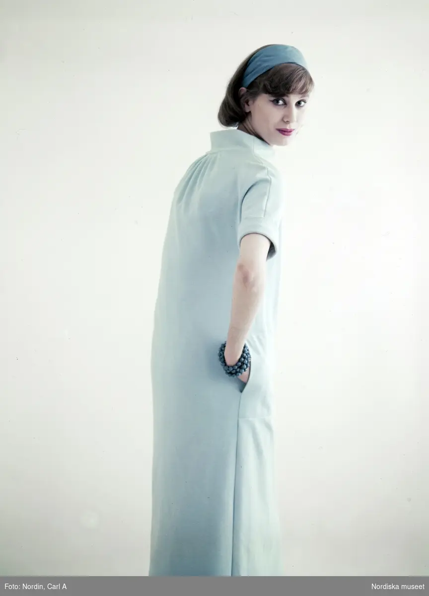 Modell i ljusblå klänning, blått hårband och armband.