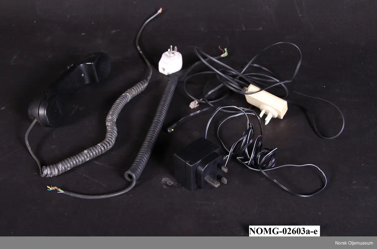 Telefonutstyr med telefonrør med ledning og tre forskjellige telefonkoblinger:
a. Telefonrør.
b. Telefonledning (svart). 
c.  Telefonadapter. (svart).
d.  Telefonadapter (hvit).
e.  Telefonadapter (hvit).