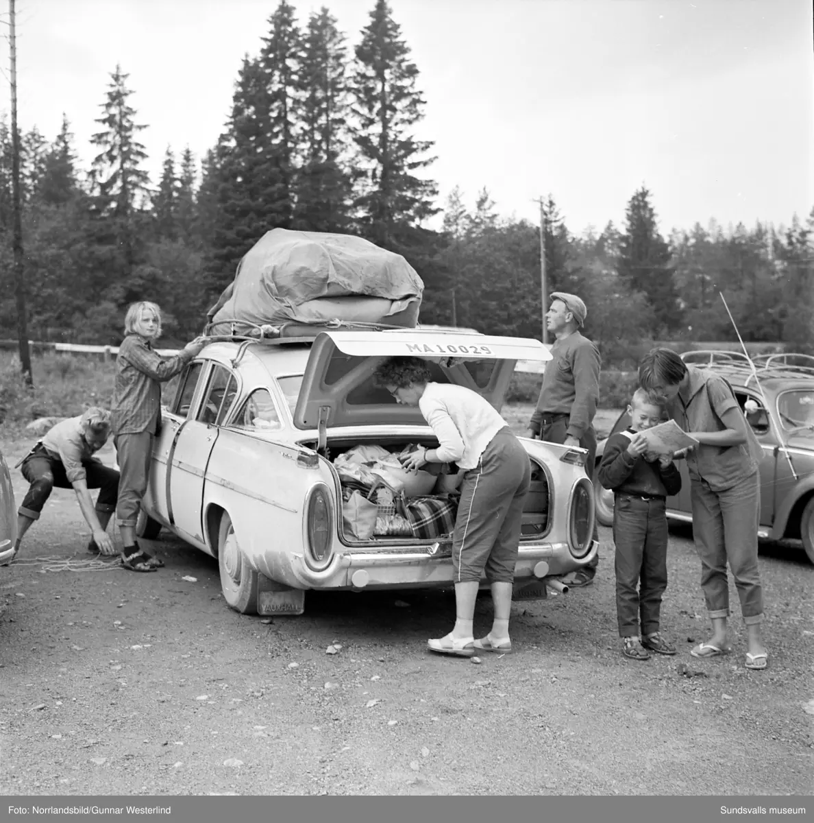 En serie bilder från Fläsians camping och badplats. Bland annat en Malmöfamilj som packar sin Vauxhall för avfärd. Tältet surras på taket av tonårssönerna och packningen stuvas i skuffen av mor i familjen. Lillebror agerar glad kartläsare medan far står i bakgrunden och ser en aning utpumpad ut.