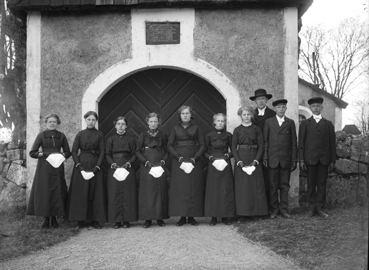 Konfirmandgrupp vid stigporten till Kungs-Husby kyrka, Uppland, sannolikt 2 maj 1914. Till höger komminister Mats Åmark (1882-1973).