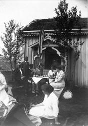 Normanfamilien samlet foran et hus med torvtak. Det er pynte